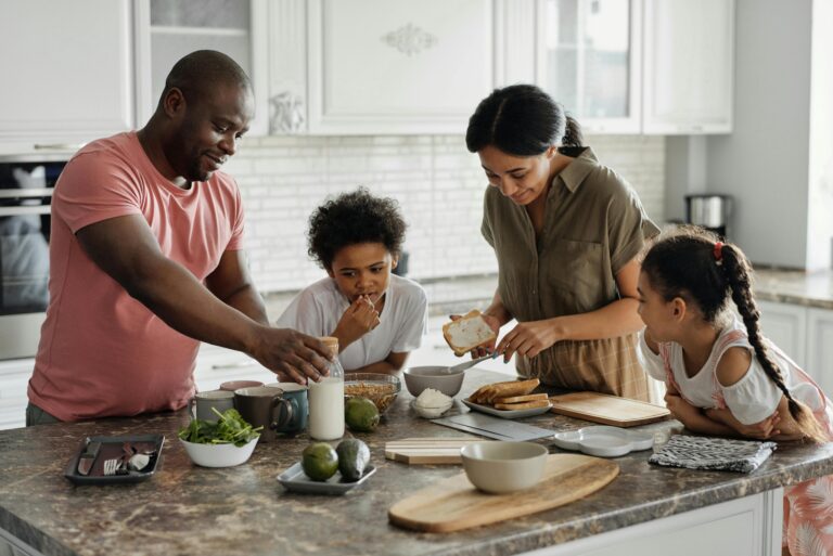 A family bonding over meal preparation in the kitchen, with ingredients spread out on the counter.
