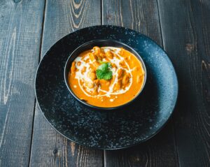A bowl of chickpea curry presented on a black plate.