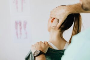 A medical practitioner examines a woman's neck during a physical check-up
