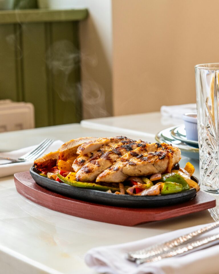 A plate of colorful food arranged neatly on a wooden table, showcasing a variety of dishes and garnishes.
