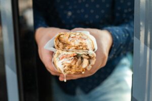 A man holding a large burrito in his hand, ready to take a bite.