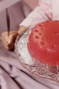  A person holds a knife above a plate featuring a colorful jelly dessert, ready to serve a slice
