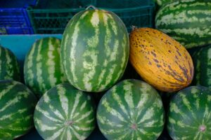  A vibrant display of multiple watermelons stacked together, showcasing their green rinds and juicy red flesh