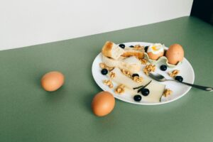  A colorful plate with eggs, cheese, and bread displayed on a green backdrop.