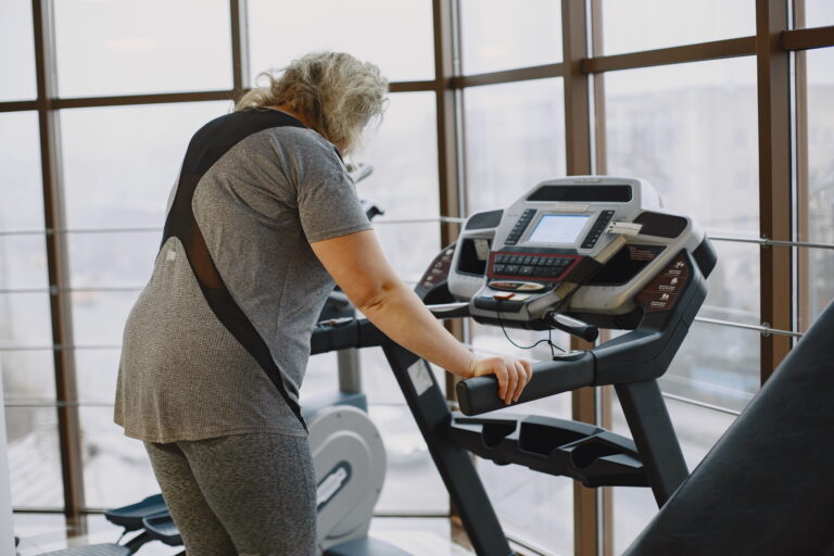 A woman exercises on a treadmill in a gym, focused on her workout
